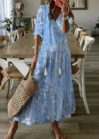 Frau in blauem Blumenkleid mit Strohtasche steht in modernem Esszimmer. Sommermode, Freizeitkleidung, Boho-Stil, Innenarchitektur.