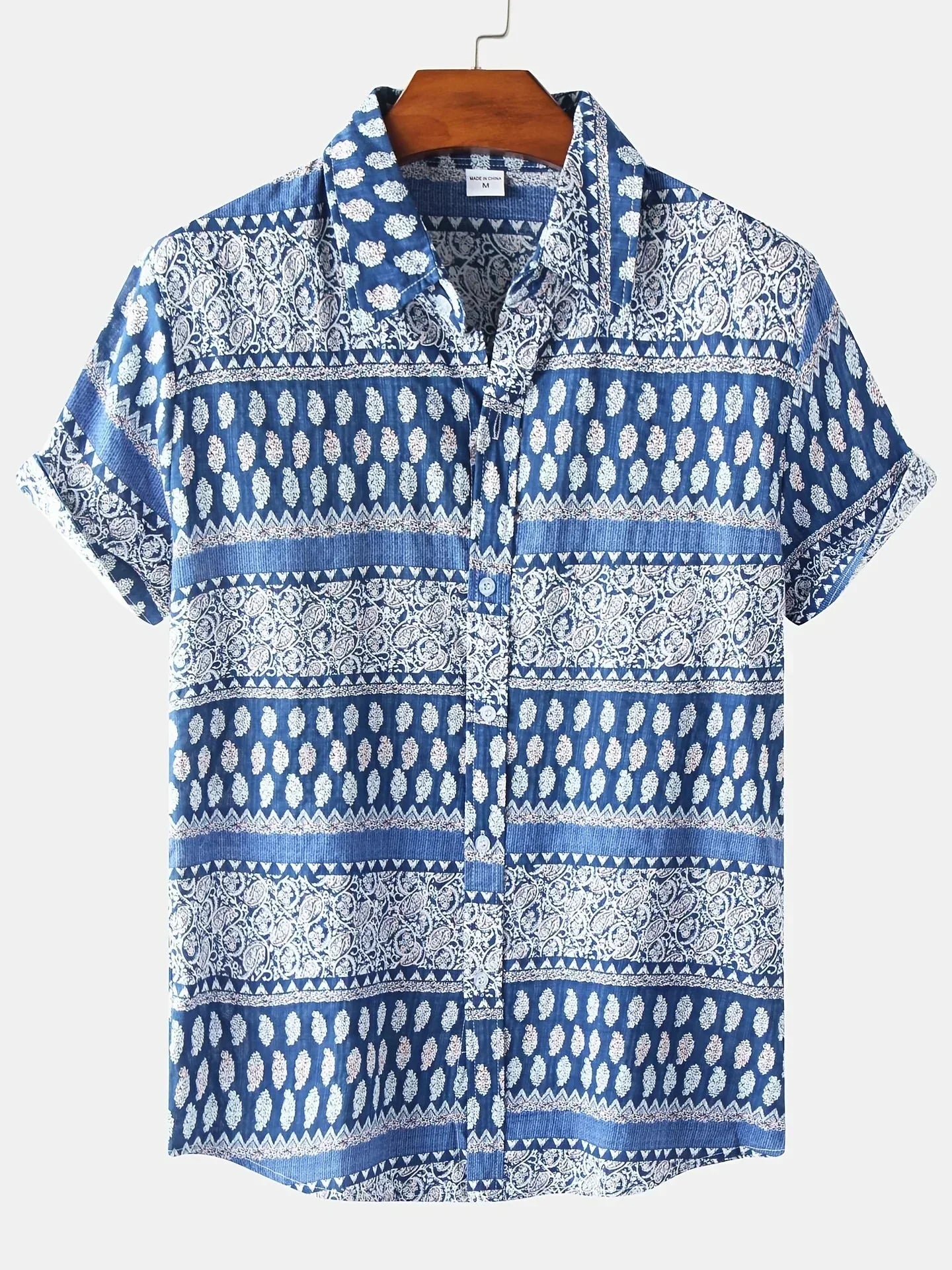 Blau-weißes Herrenhemd mit Paisley-Muster, kurzärmelig, aus Baumwolle, auf Holzkleiderbügel. Ideal für Sommermode und Freizeitkleidung.
