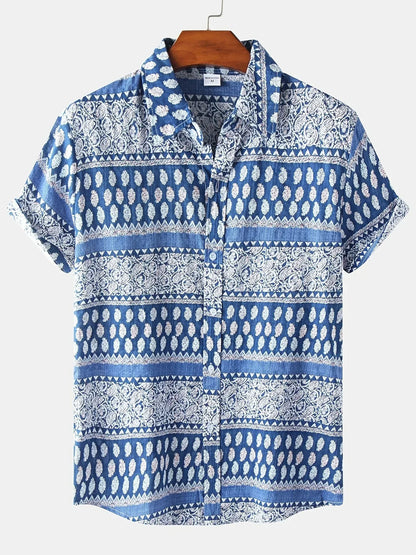Blau-weißes Herrenhemd mit Paisley-Muster, kurzärmelig, aus Baumwolle, auf Holzkleiderbügel. Ideal für Sommermode und Freizeitkleidung.