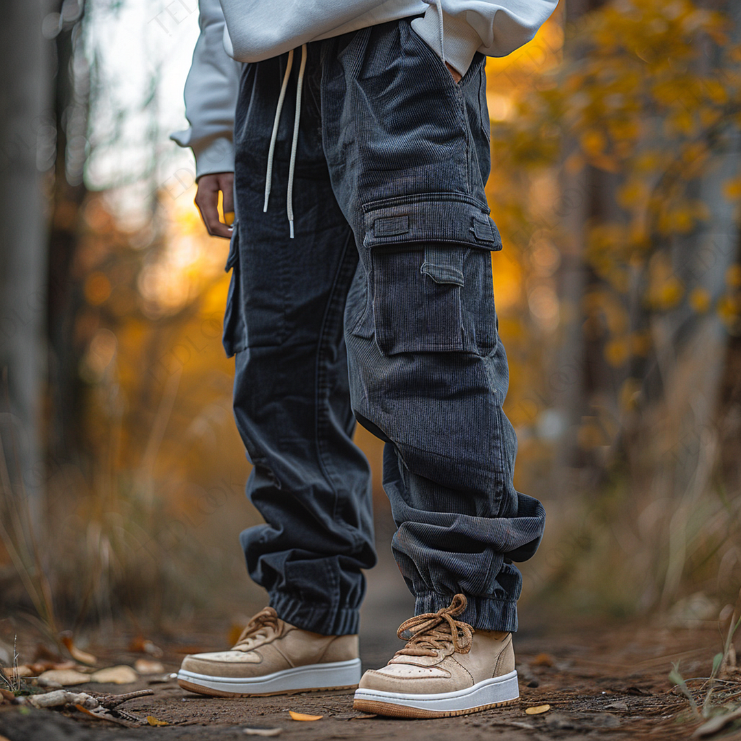 Person trägt schwarze Cargohose und beige Sneaker im herbstlichen Wald. Modetrend, Outdoor-Style, Freizeitkleidung, Herbstmode, Natur.