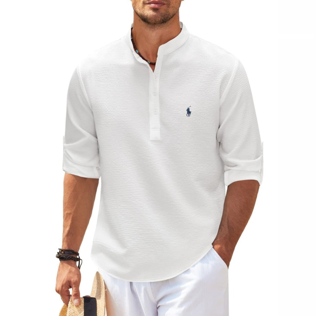 Mann in weißem, langärmligem Polohemd mit Stehkragen, hält Strohhut. Sommermode, Freizeitkleidung, eleganter Look.