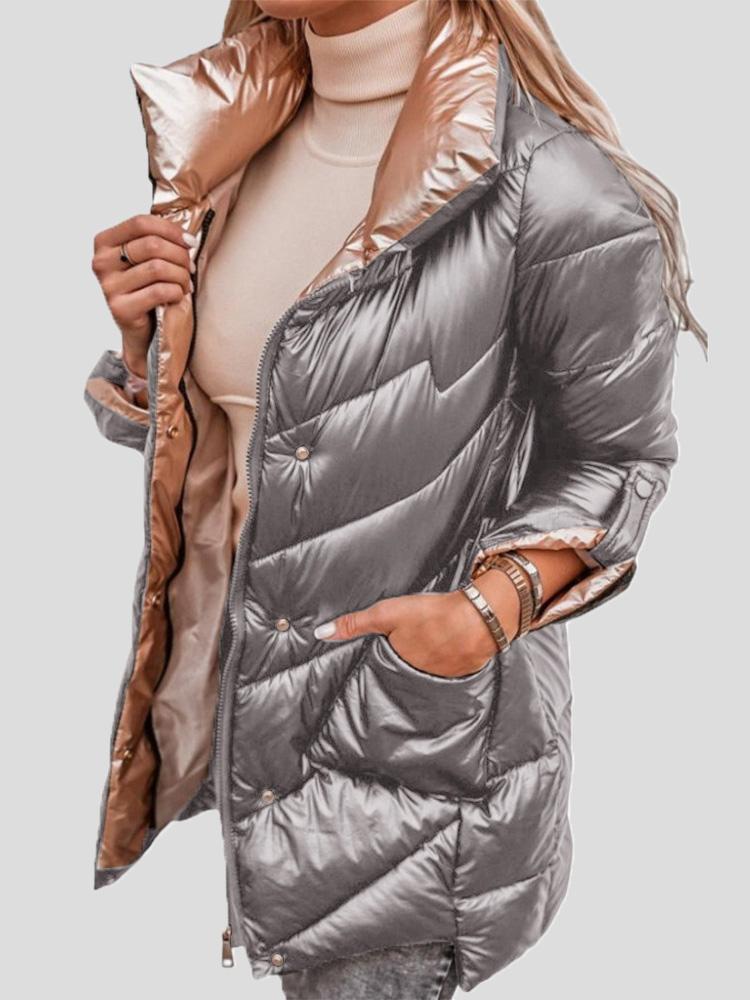 Silberne Damen-Daunenjacke mit glänzendem Finish, Reißverschluss und Taschen, kombiniert mit beigem Rollkragenpullover. Wintermode, stilvoll und warm.